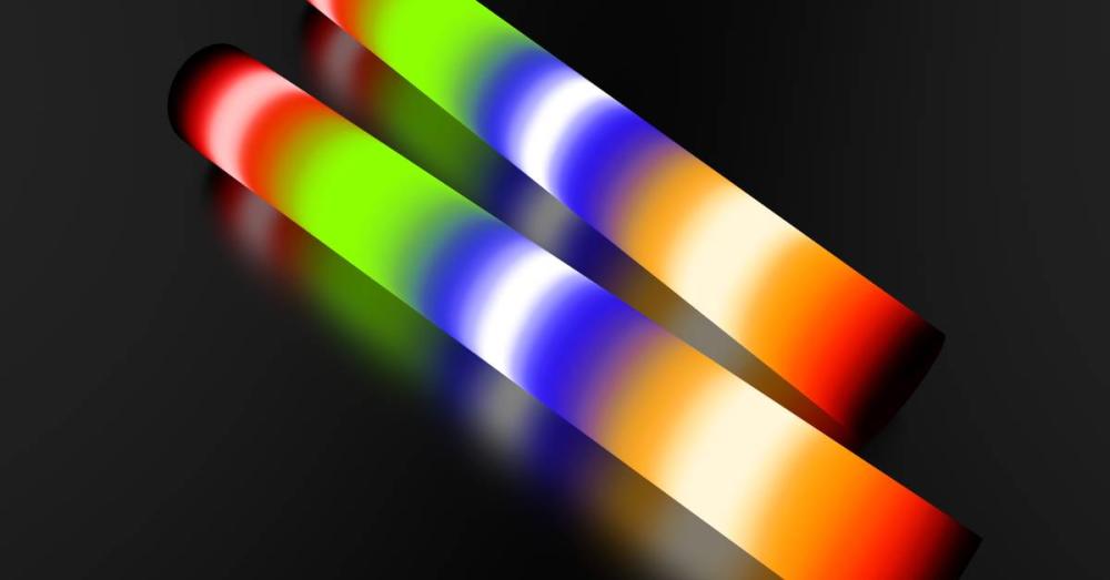 Two light-up batons against a dark background. They are lit up in a multi-colored pattern with white separating the colors.