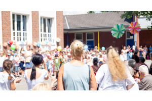 A community gathered for a school fundraising event. There are decorations and crowds of kids watching a performance.