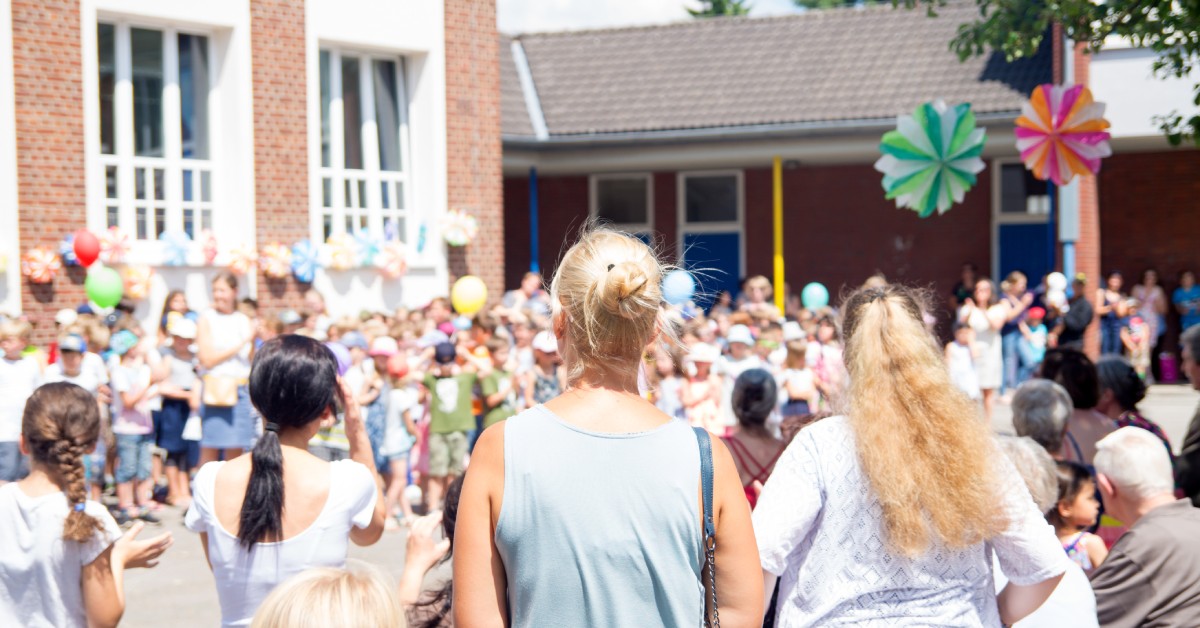 A community gathered for a school fundraising event. There are decorations and crowds of kids watching a performance.