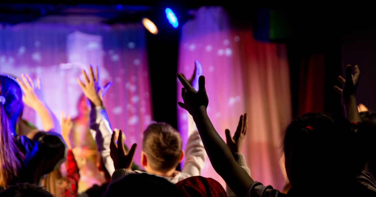 A student event at night with a large crowd. There is a performance onstage with lighting on the stage and the audience.