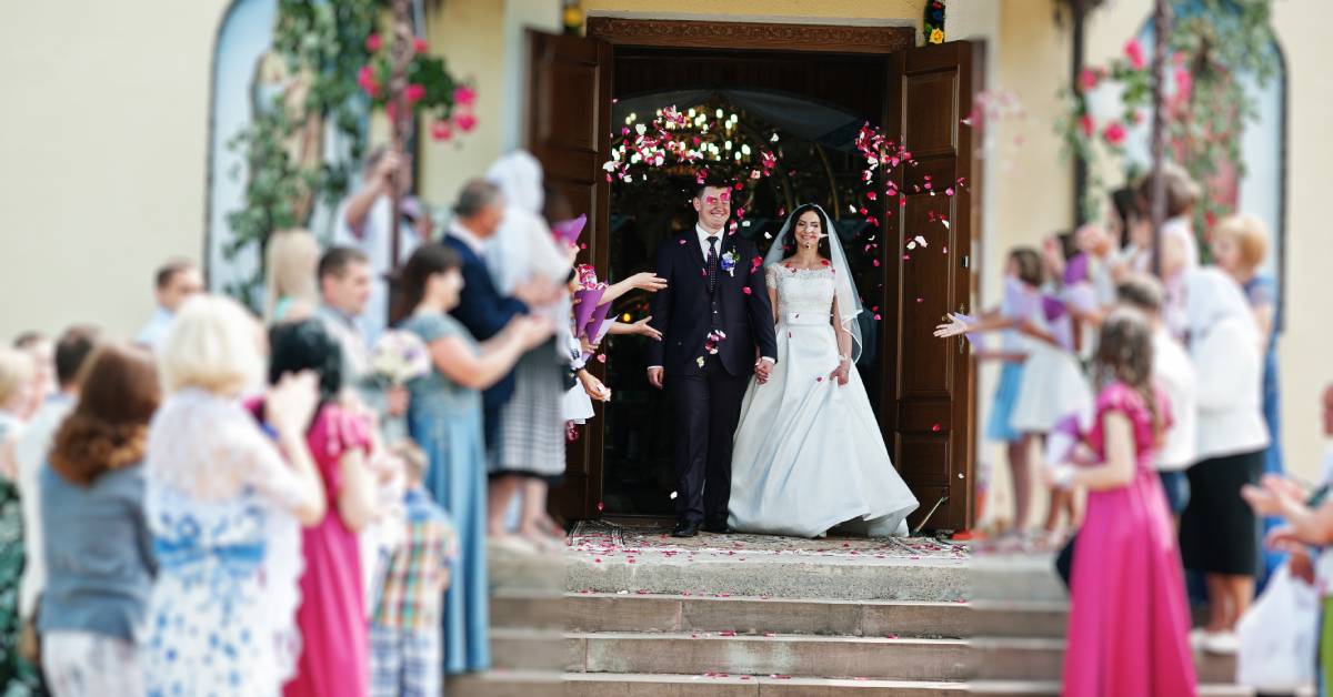 Newlyweds leaving their ceremony with their guests throwing flower petals as they walk out. The petals are white and red.